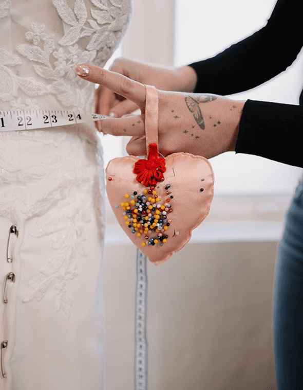 Tailor adjusting delicate fabric on a bridal dress during a fitting