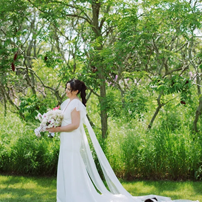 Happy bride posing in a lush green garden wearing her altered wedding dress