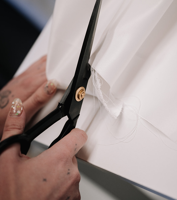 Close-up of tailor cutting fabric with professional scissors for custom bridal alterations in Toronto